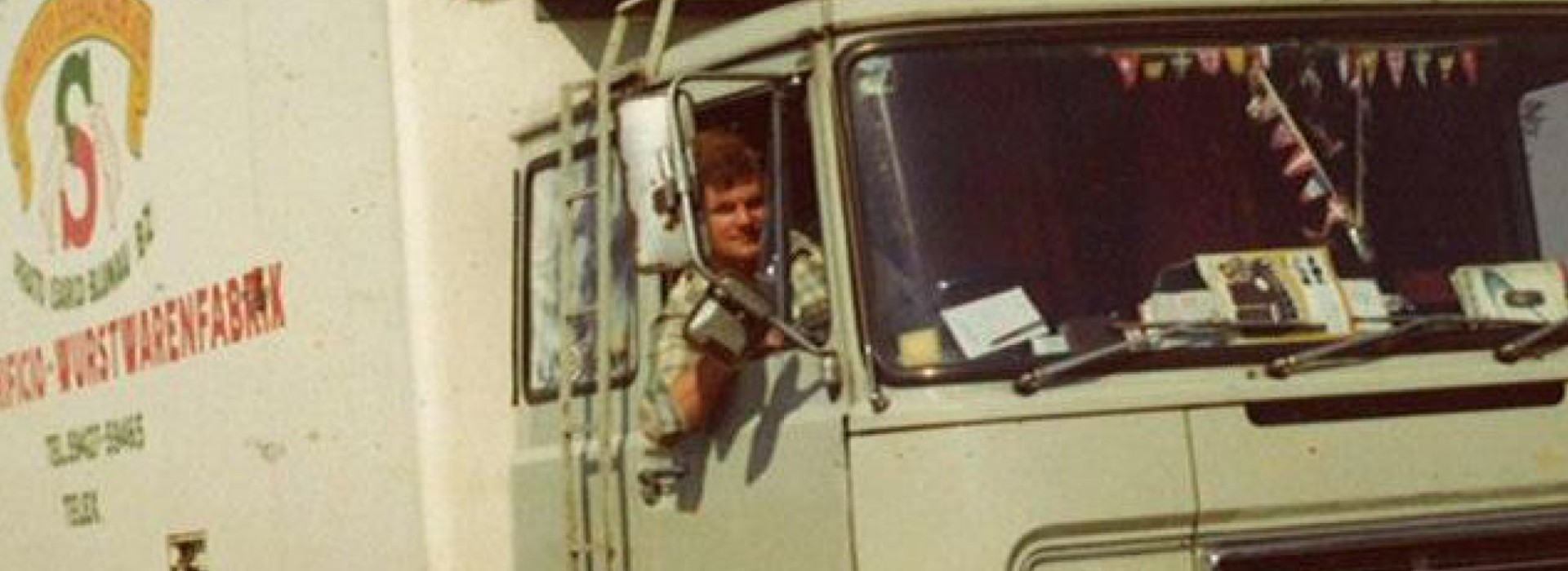 Ein Fahrer lenkt einen Lkw von Transbozen. Am Auto sieht man, dass das Bild einige Jahrzehnte alt ist.